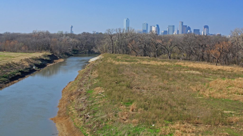 The Trinity River flows in the foreground and the Dallas, Texas skyline can be seen on the horizon.