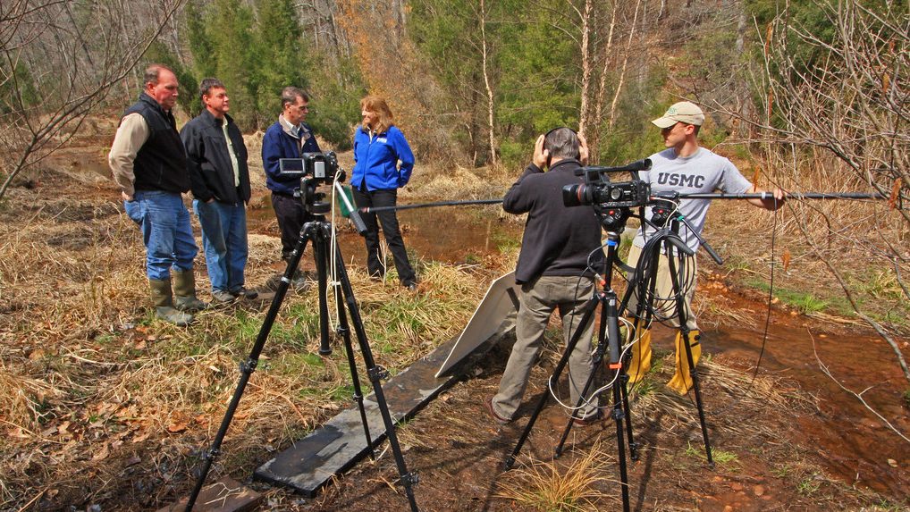 People filming interview on river bank
