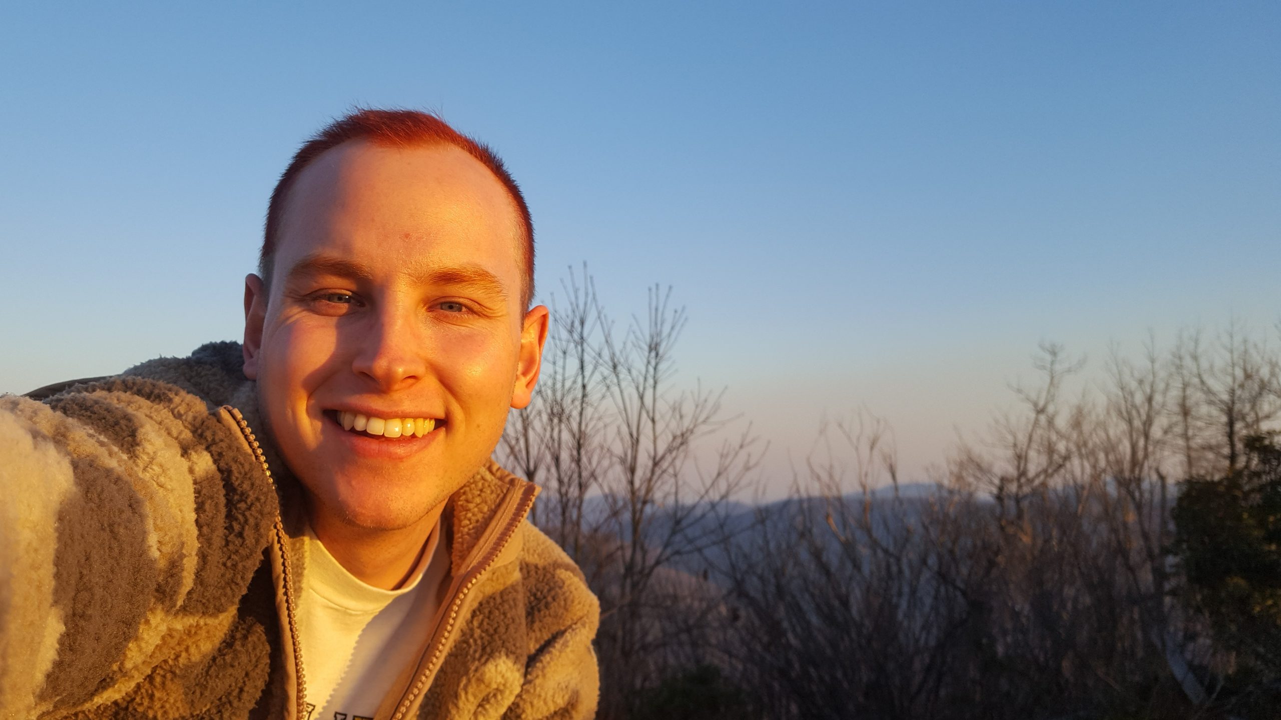 young man smiling with view of mountains behind him