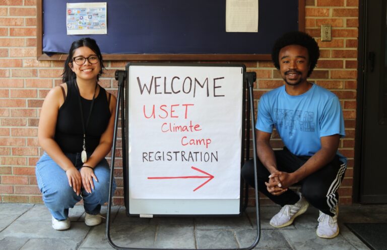 Interns Eleana and Zavier next to a registration sign for Tribal Climate Camp